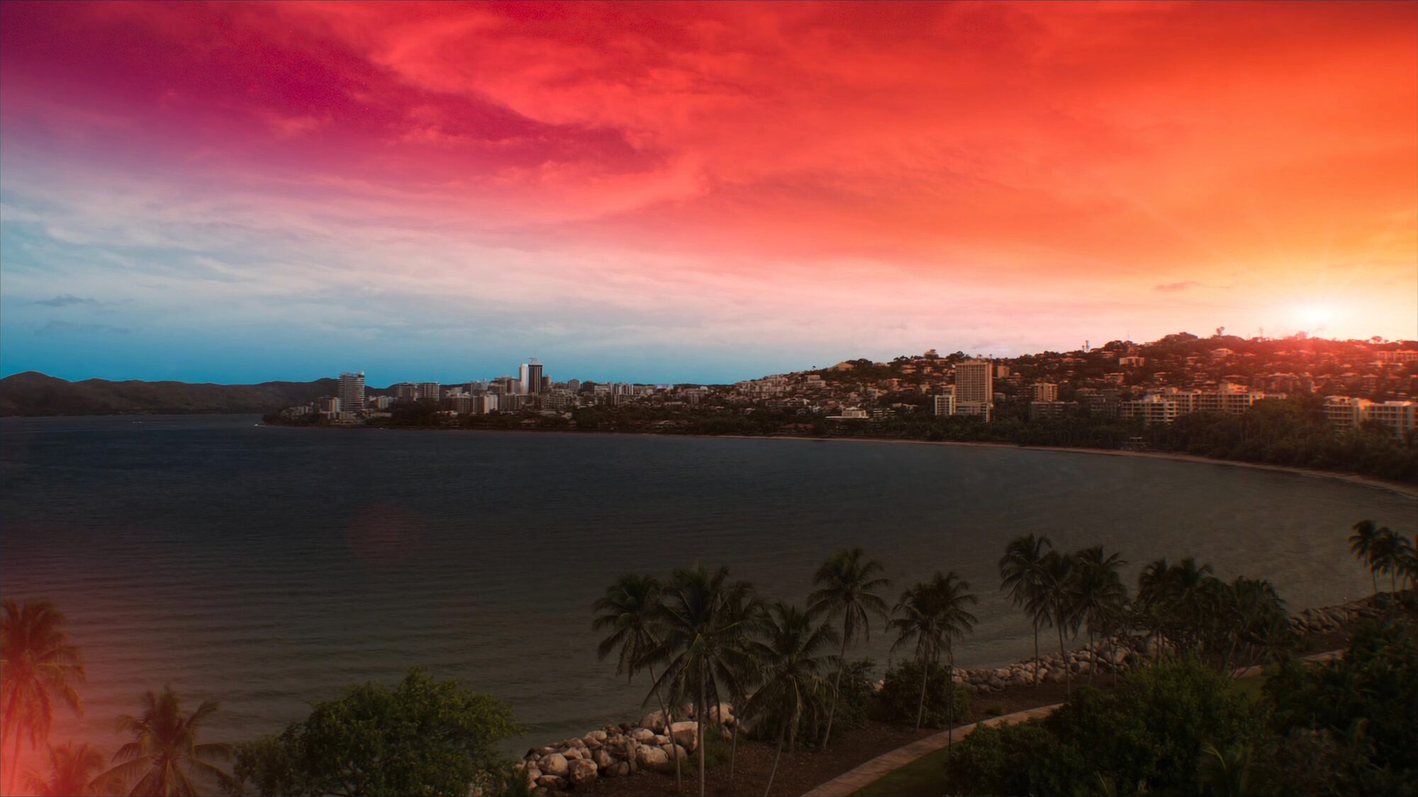 The Darwin coastline and harbour suburbs spread out under a coral and gold Top End sunset
