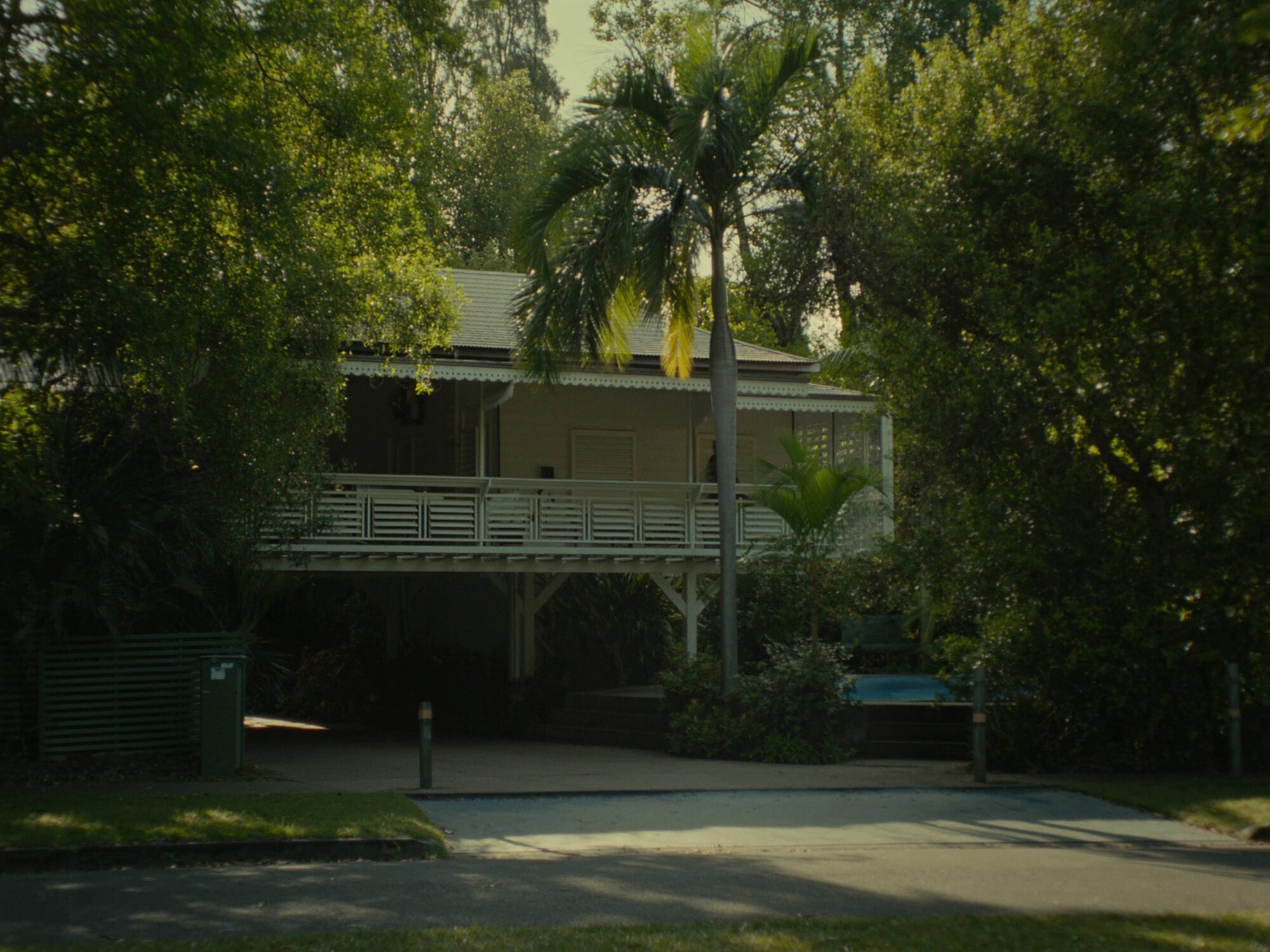 Elevated Larrakeyah troppo home with full-width louvred verandahs framed by mature palms